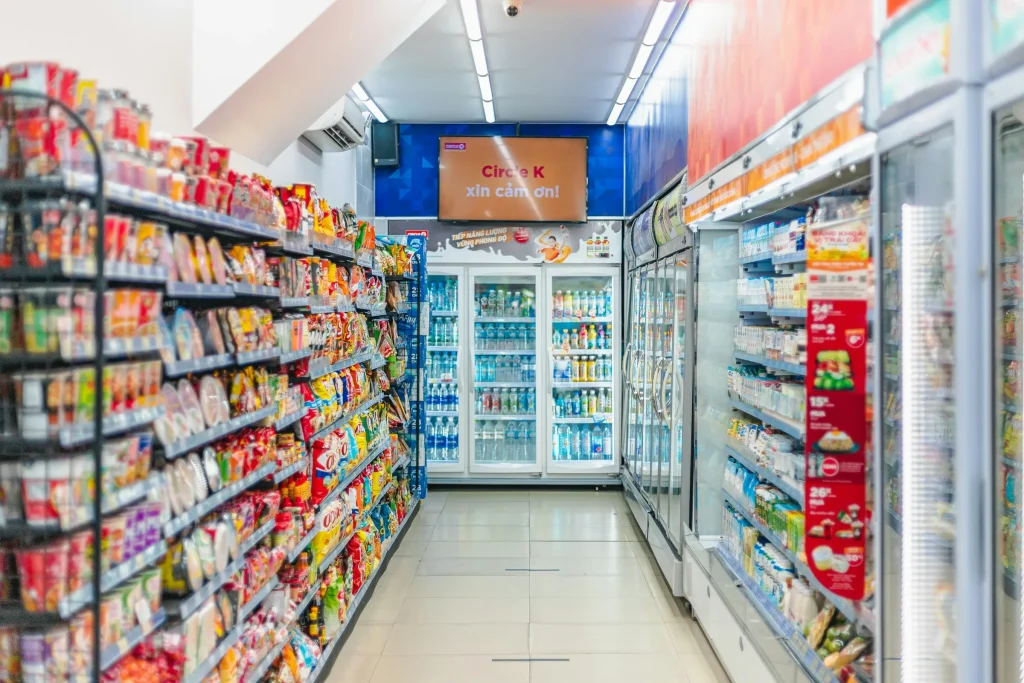 Well-stocked convenience store aisle with snacks and drink coolers