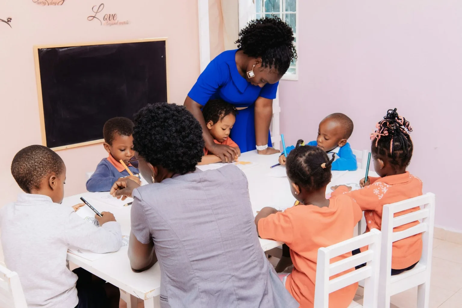 Child Care Funding 7 Daycare teacher helping young children with an activity at a classroom table