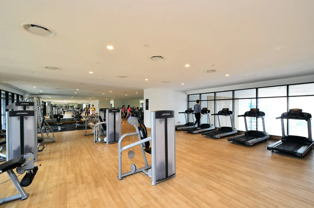 Bright fitness center with treadmills and strength equipment on a wood floor