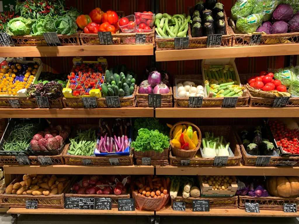 Fresh vegetables and fruit displayed on shelves in a grocery store produce section