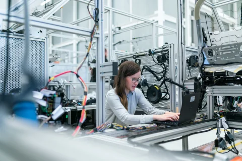 Technician operating a CNC machine on a modern manufacturing plant floor