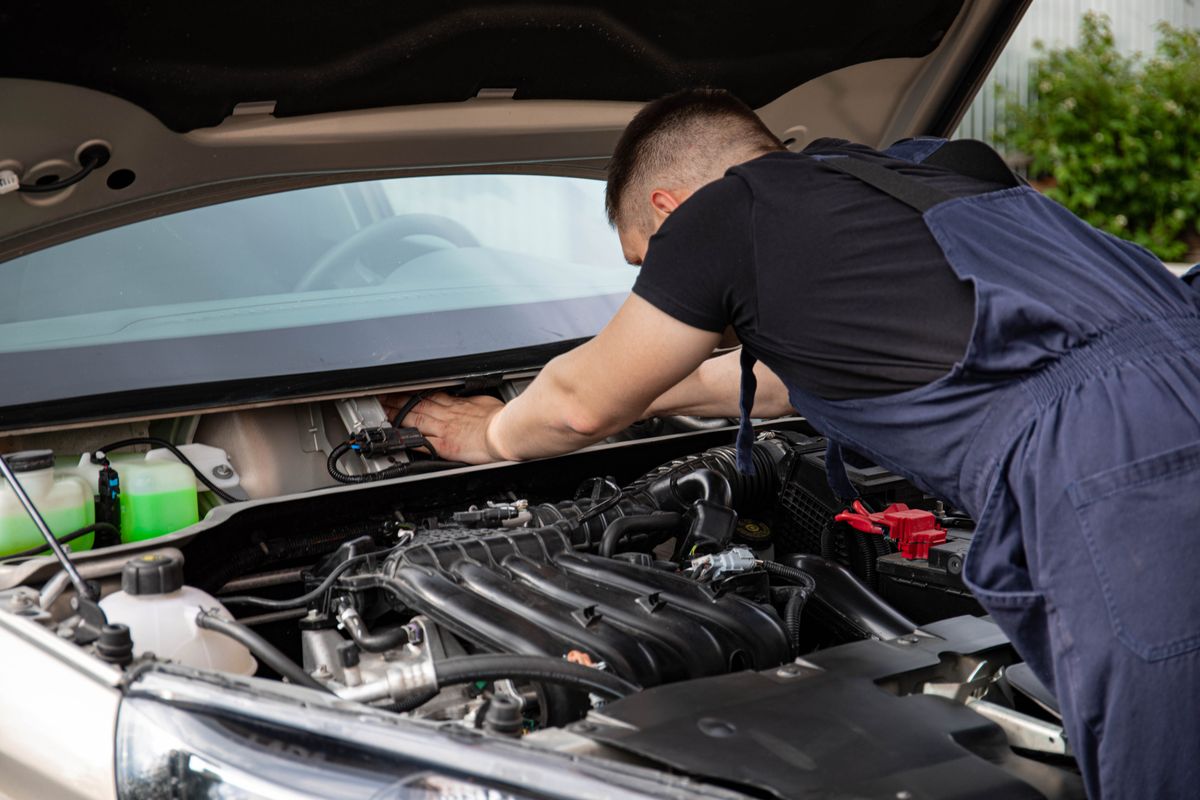 Mechanic working under the hood of a car in a repair shop