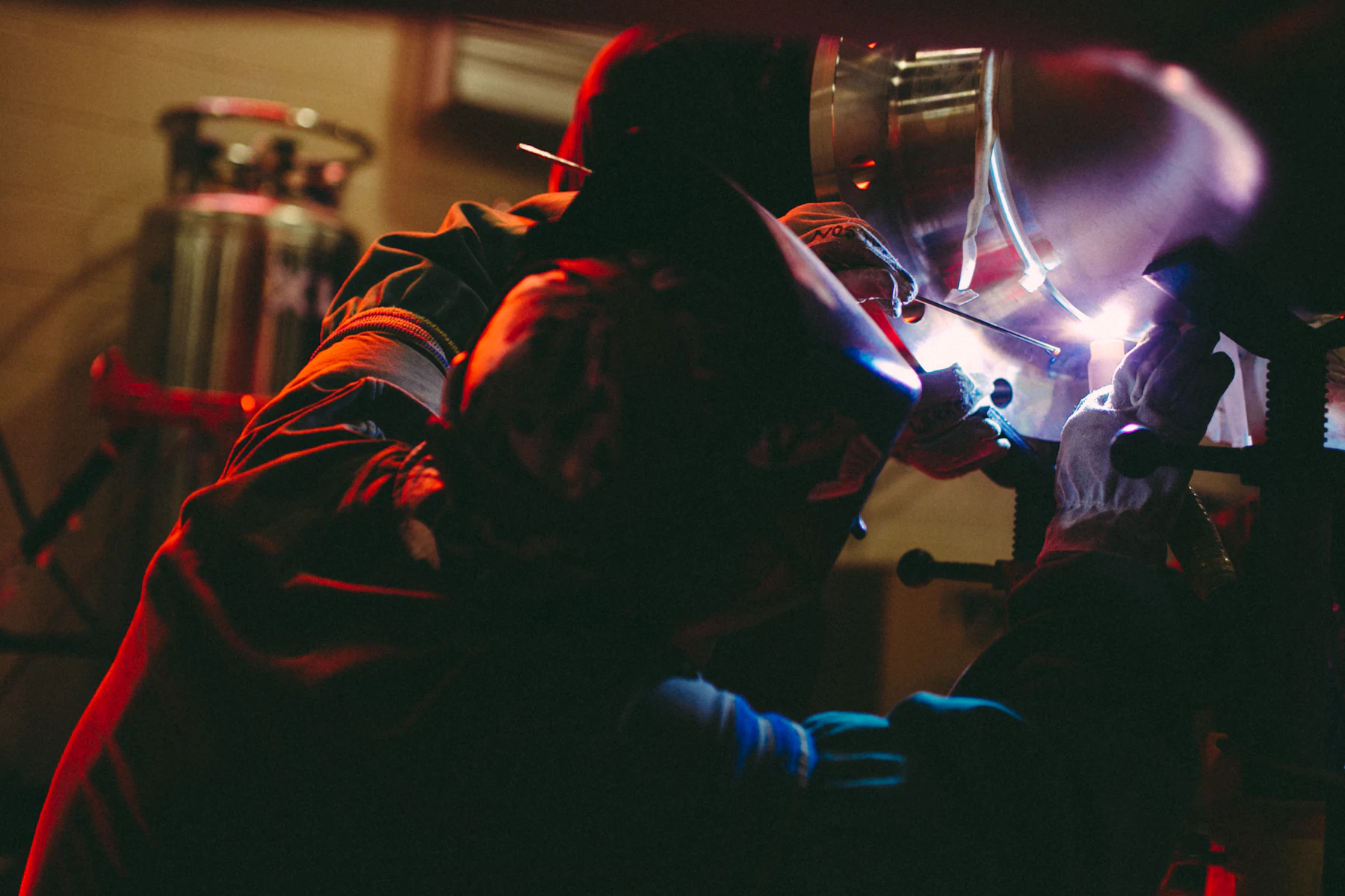 How Hard Is It to Get a $1,000,000 Business Loan? 2 Person welding metal inside a lit building