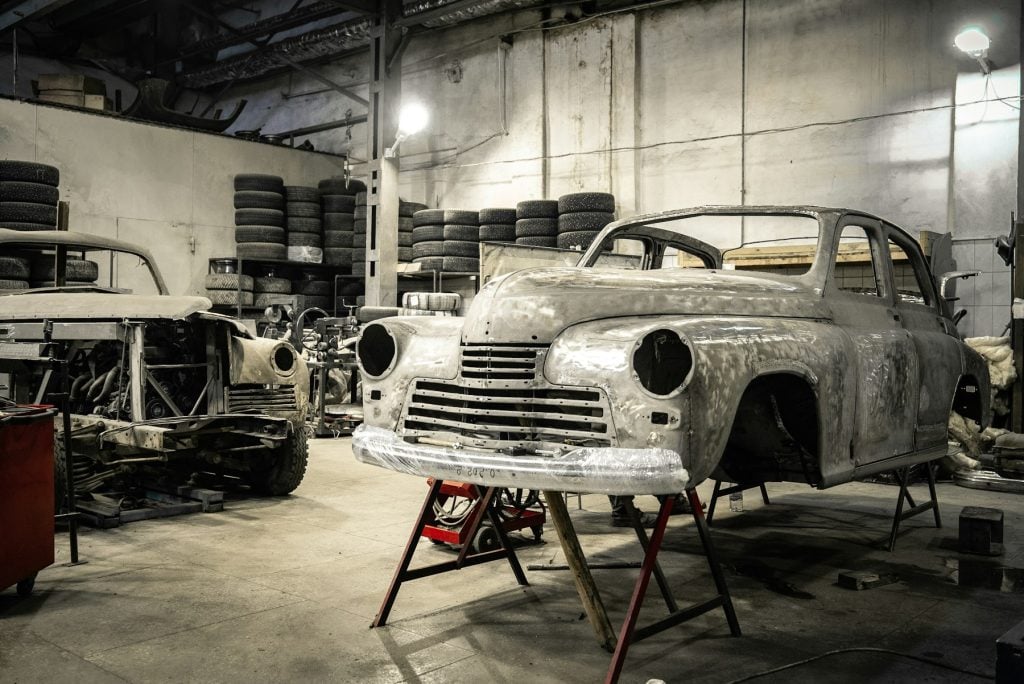 Classic car body stripped to bare metal inside an auto body shop
