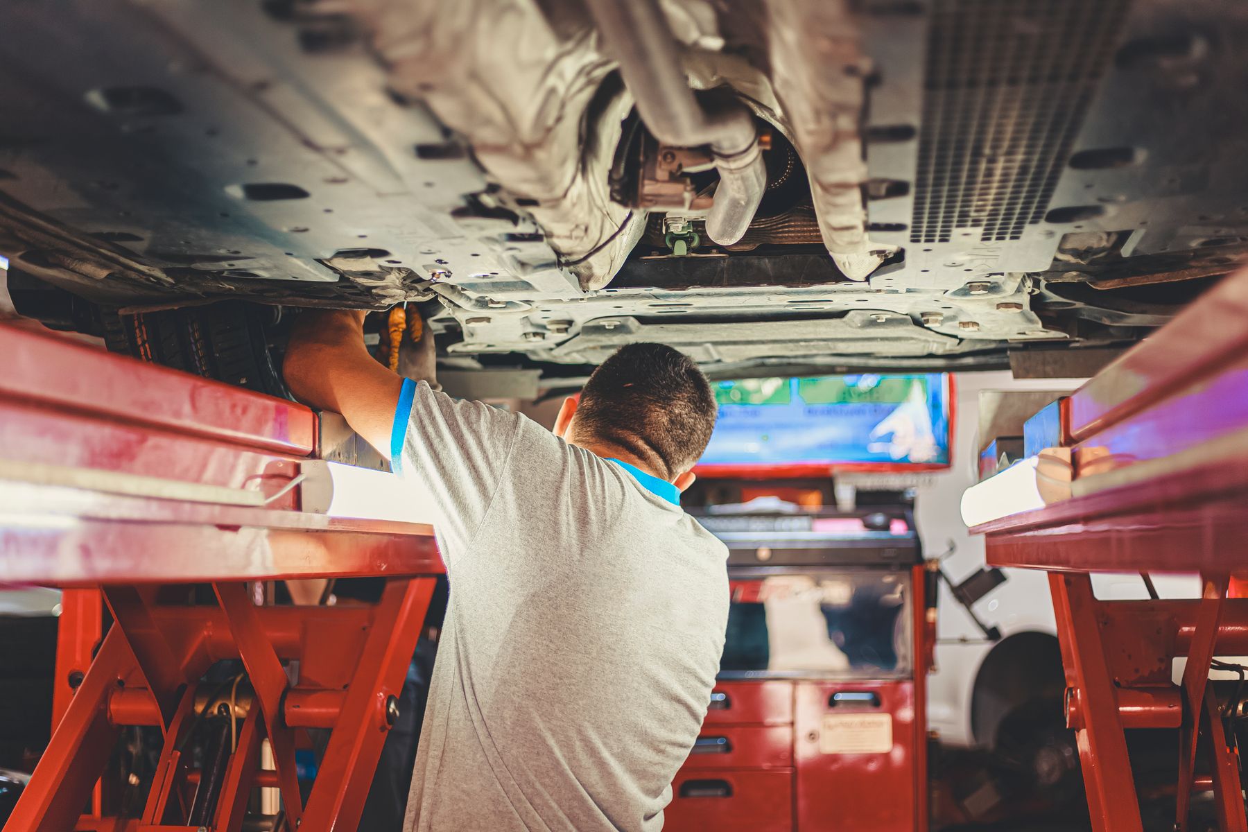 Auto Repair Shop Equipment Financing: Lifts, Alignment, Diagnostics and Paint Booths (2026) 2 Mechanic working under a lifted car in an auto repair shop
