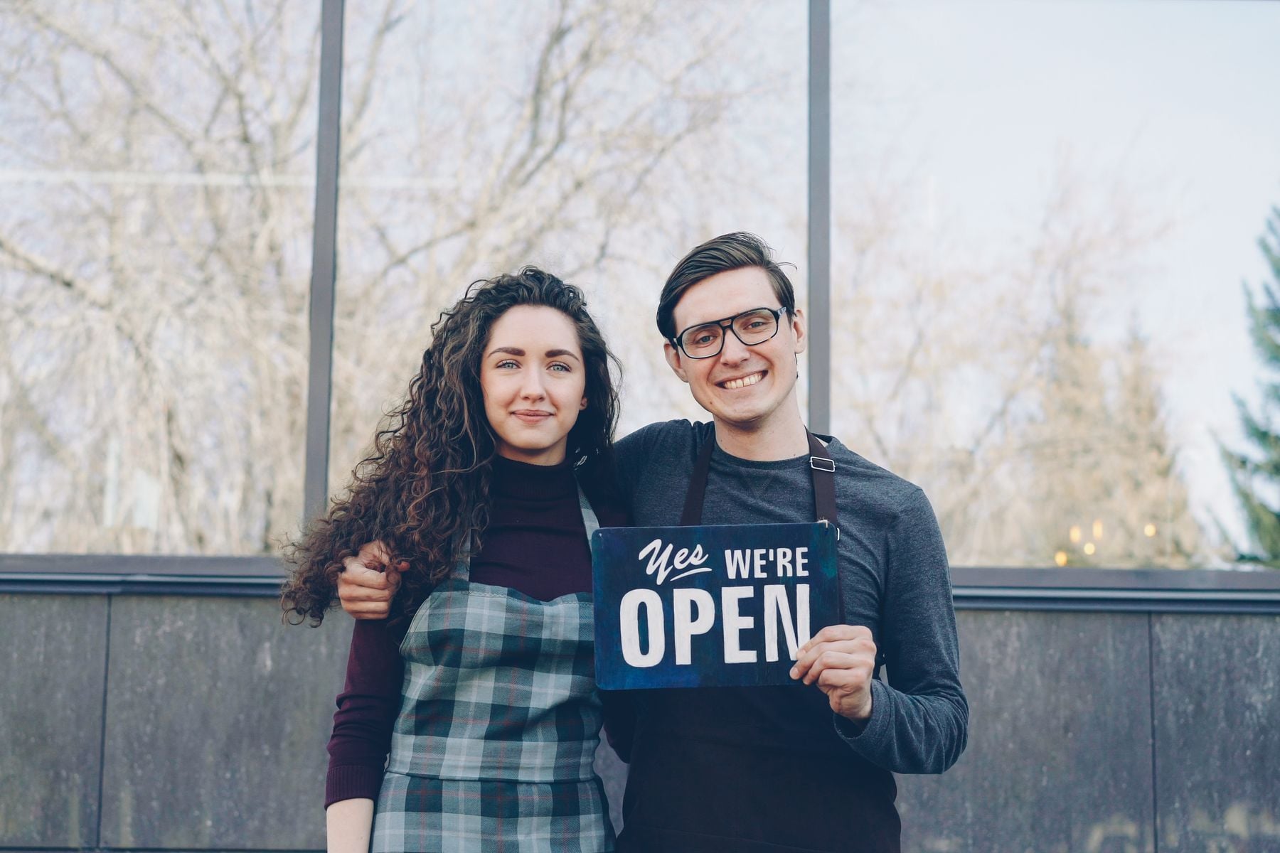 How Soon Can I Borrow Again After Paying Off a Business Loan? 2 Two small business owners holding an open sign at their shop