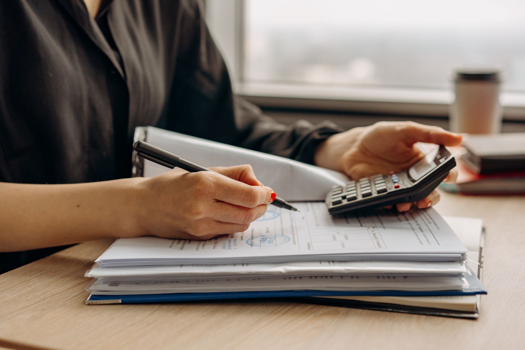 Business Loan Fees Explained: Origination, Draw, Prepayment, SBA Guarantee and the Fees Hidden in Factor Rates (2026) 2 Calculating loan fees with a calculator and documents