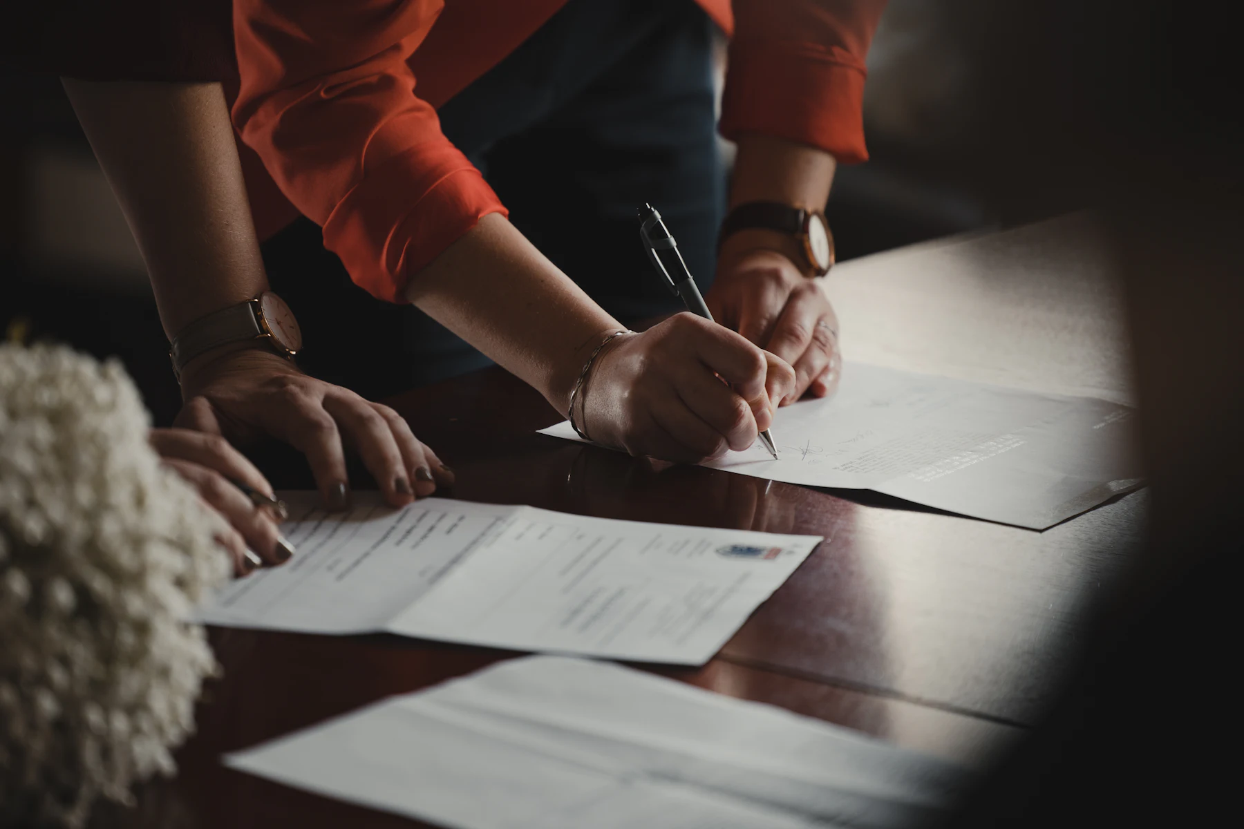 Business Loan Referral Fees: How Referral Partners Get Paid 2 Person in an orange long-sleeve shirt writing on white paper