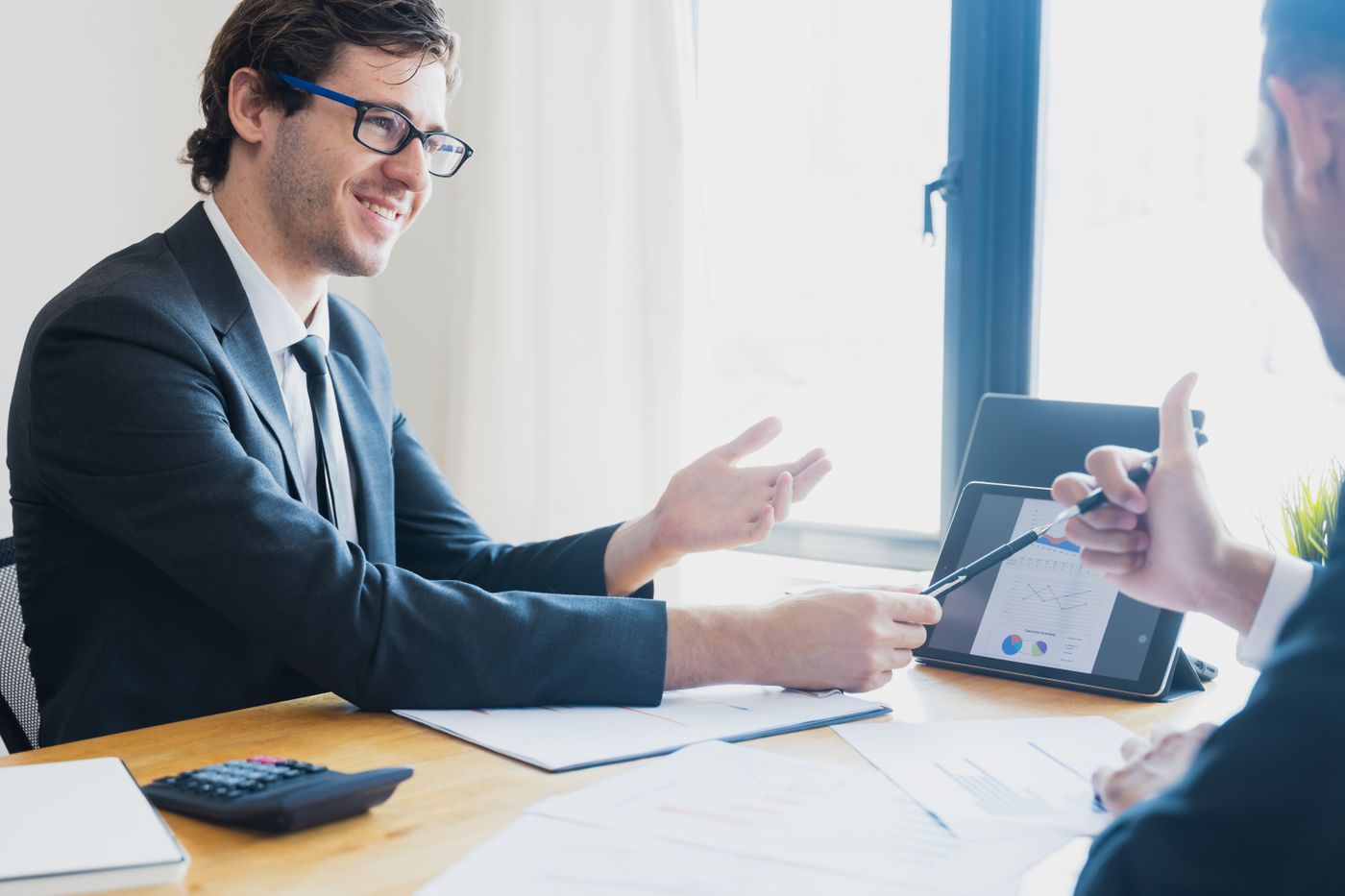 Business Loan Referral Program for Business Brokers and M&A Advisors 2 Business broker reviewing a sale report with a client at a desk