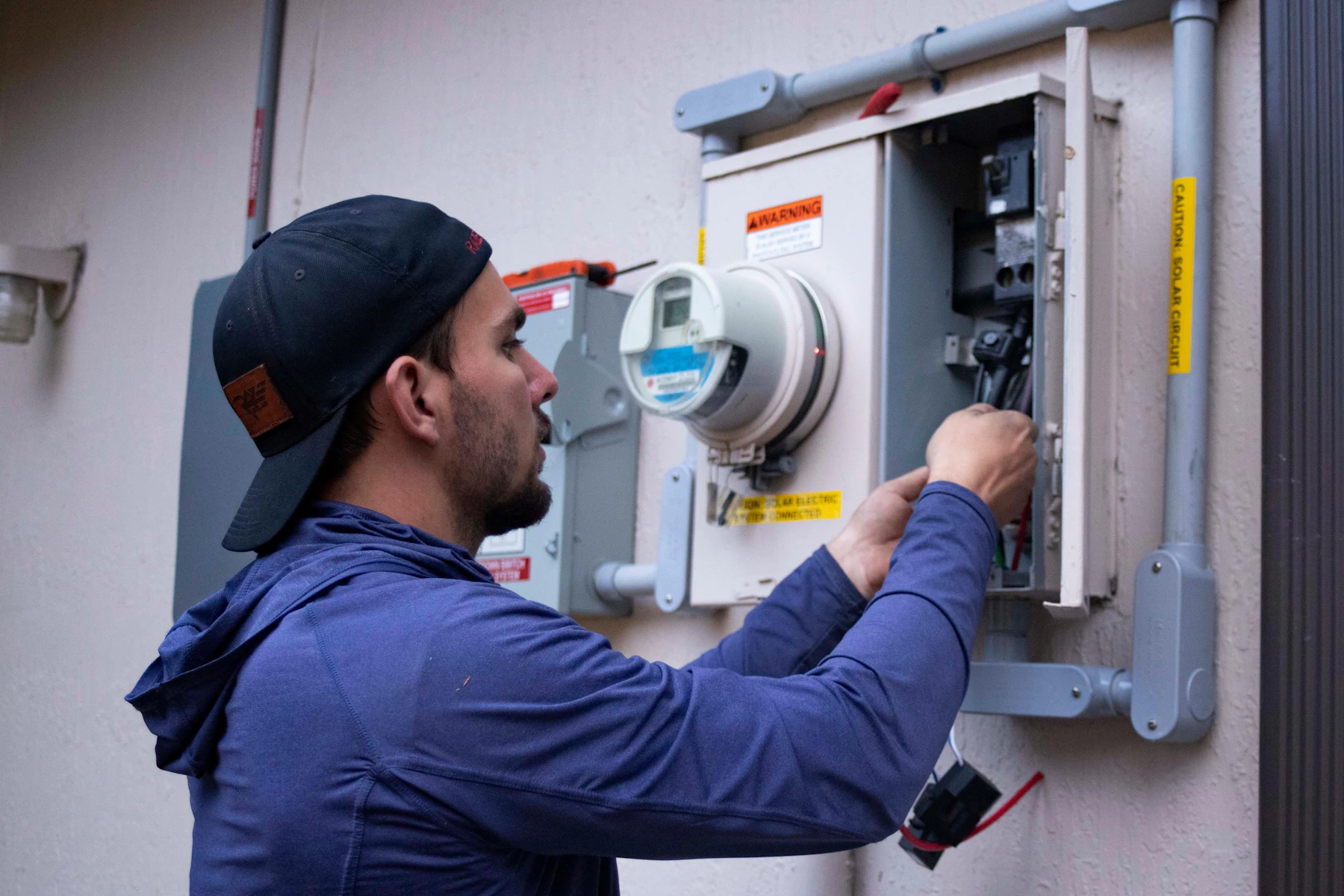 Business Loans in 24 Hours: Timeline, Requirements and How to Qualify 2 Person in a blue hoodie and baseball cap working on an electrical meter