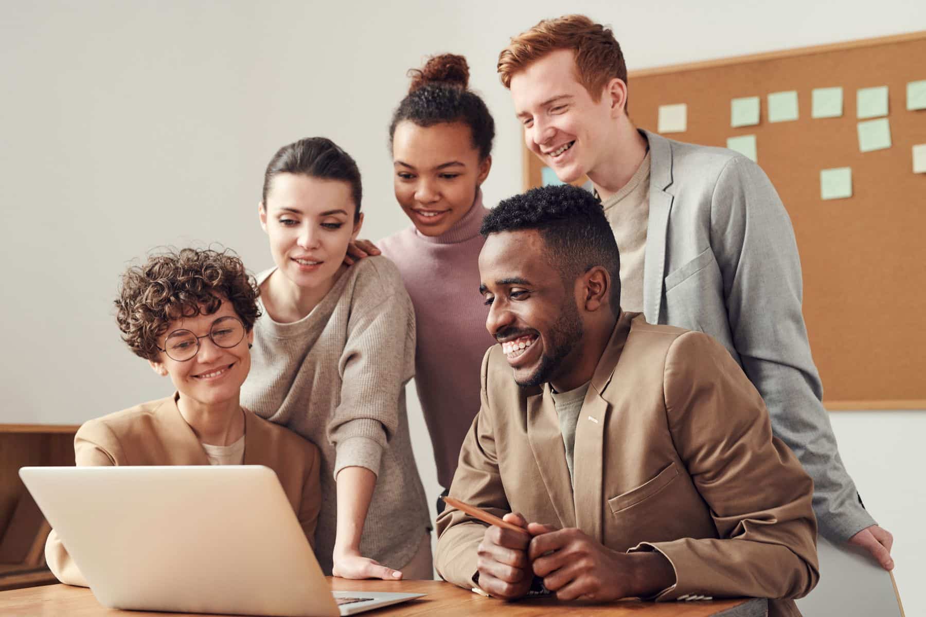Smiling business owners gathered around a laptop in an office