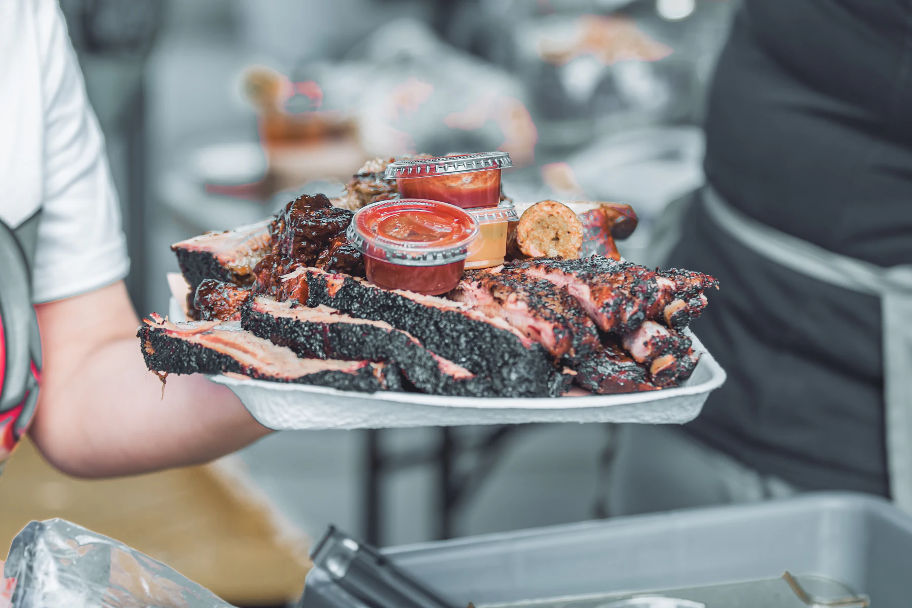5 Razones por las que los Dueños de Negocios en Misisipi Buscan Financiamiento en 2026 2 Persona sosteniendo una bandeja de costillas a la barbacoa
