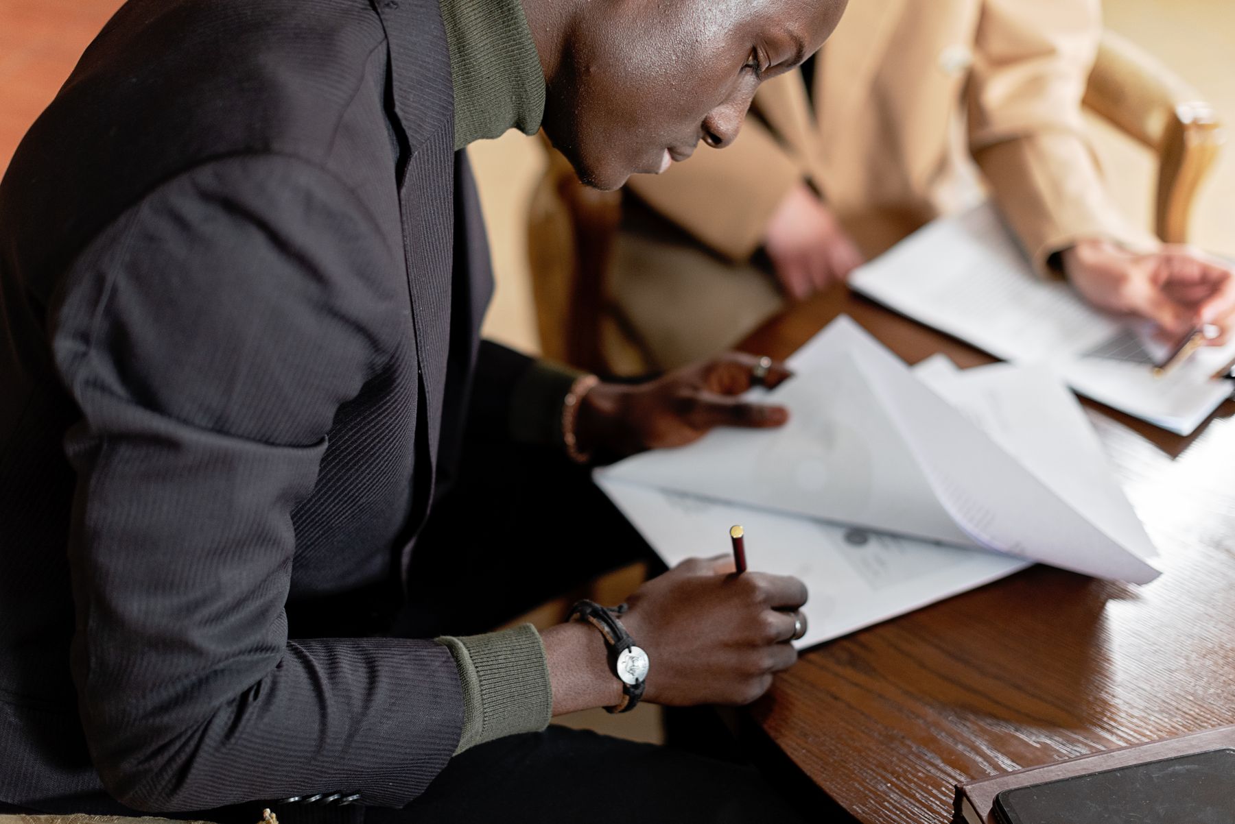 How Hard Is It to Get an SBA Loan? 2 Business owner signing SBA loan application documents at a desk