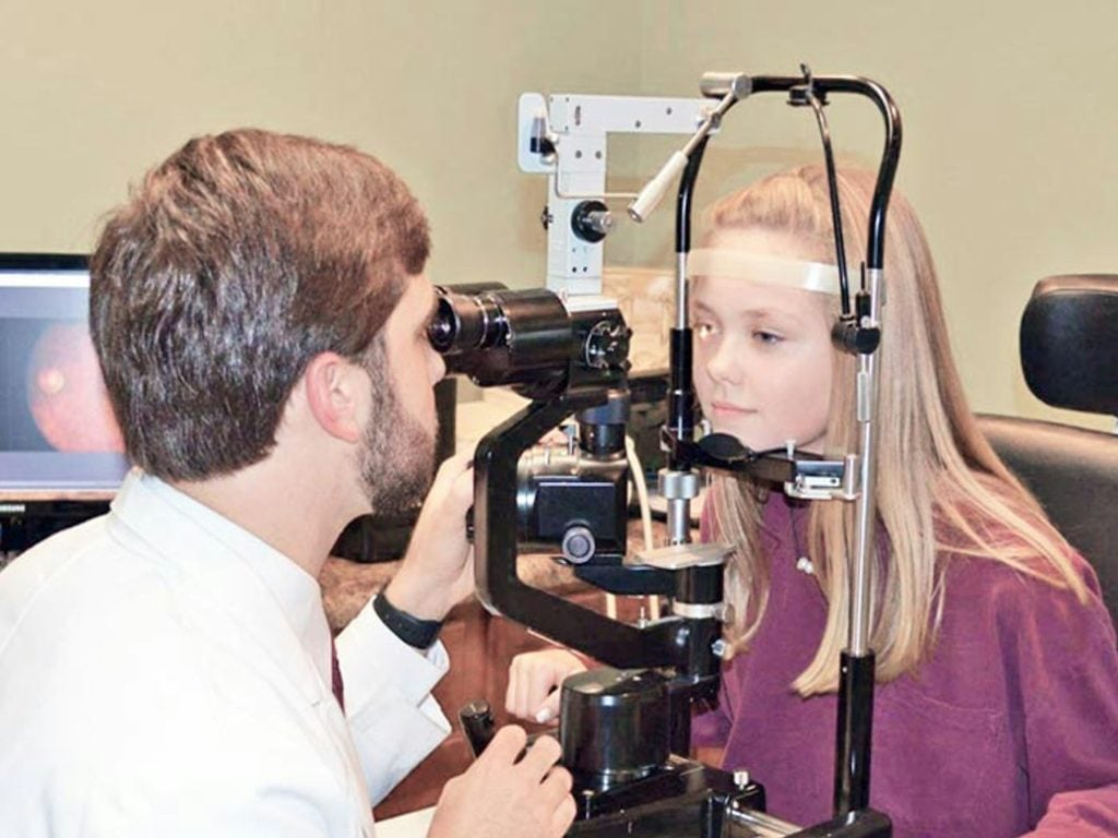Optometrist examining a patient’s eyes at a slit lamp
