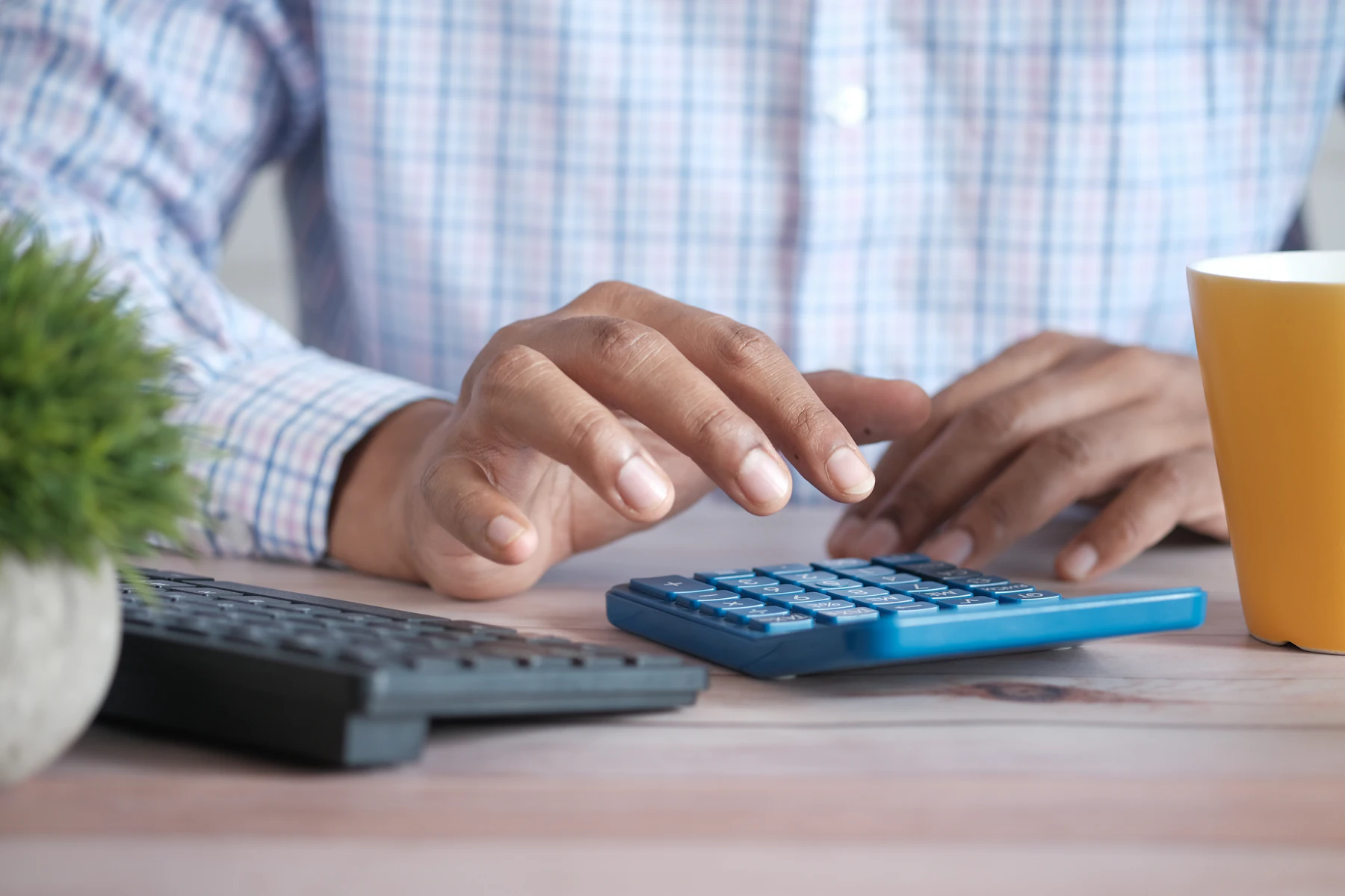 Préstamo de Negocio para Pagar Impuestos: Opciones de Financiamiento para una Deuda Fiscal 2 Persona usando una calculadora en su escritorio junto a una taza de café