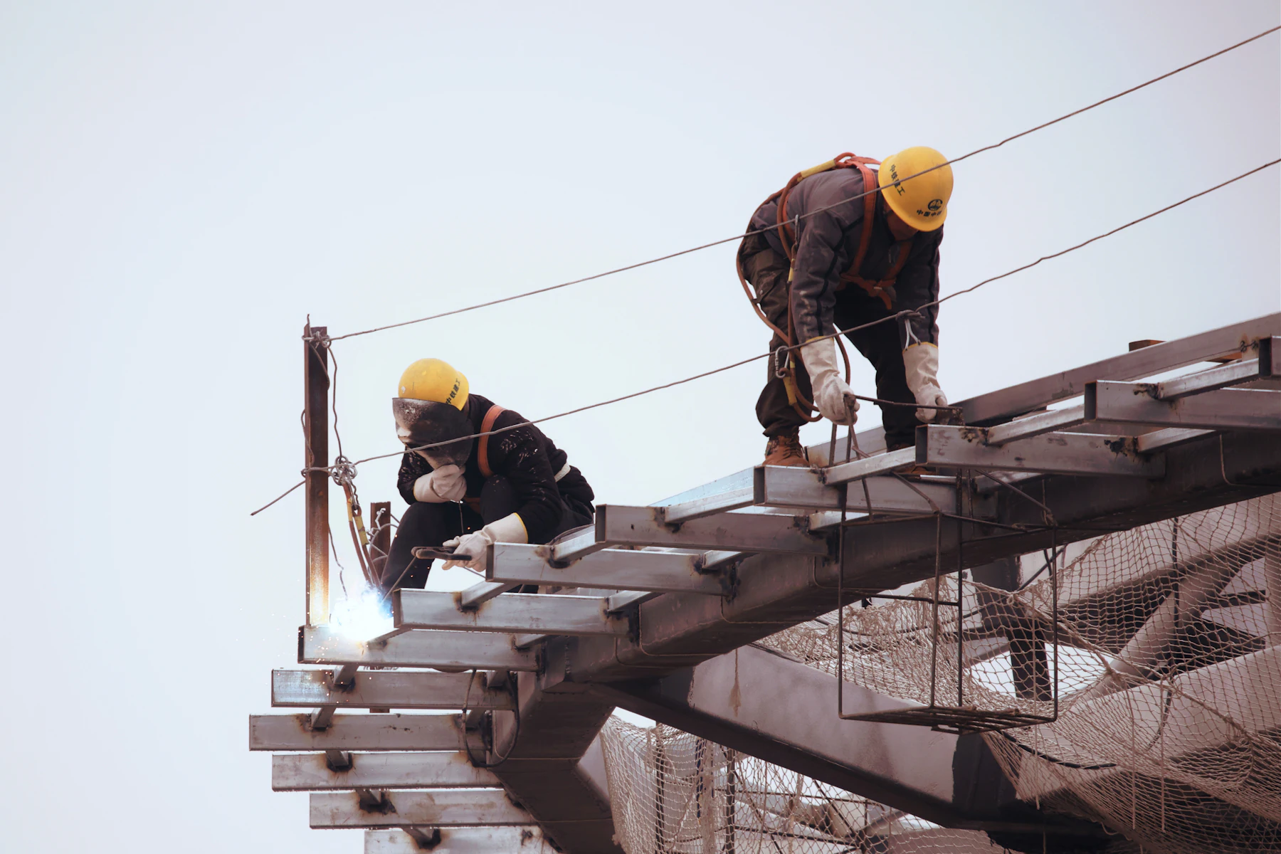 Préstamos para Negocios de Construcción 2 Trabajadores con casco sobre la estructura de un techo