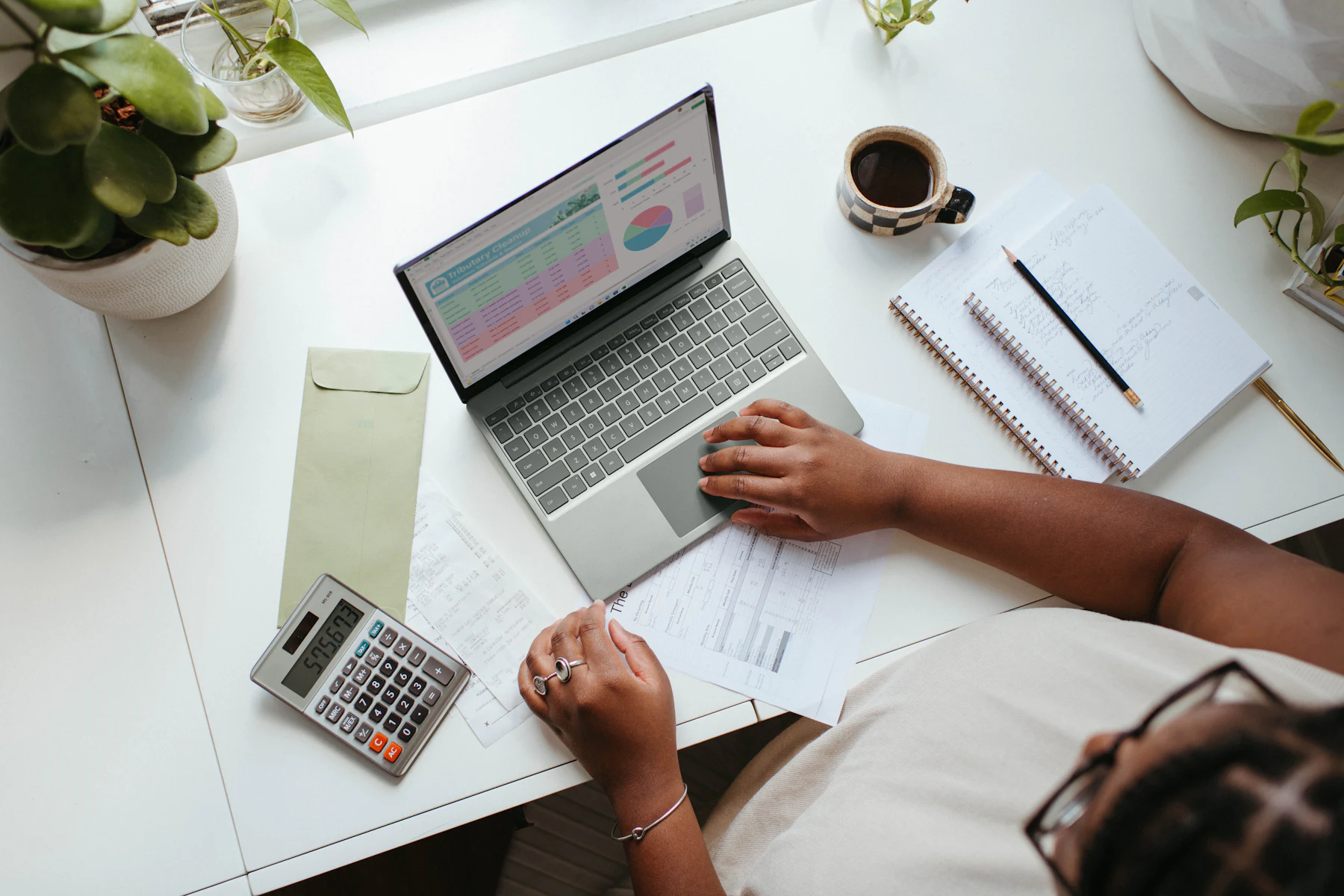Préstamos para Negocios en Línea: Cómo Funcionan y Cómo Calificar 2 Vista superior de una persona trabajando con una computadora portátil y una calculadora