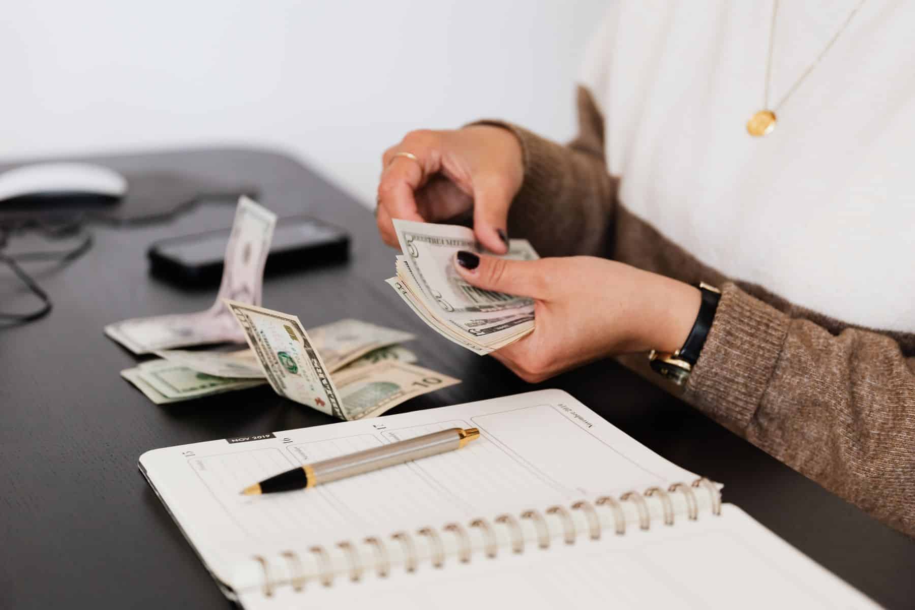 Prime Rate Is 7%: What the Fed Hike and the October 28 FOMC Mean for Business Loan Rates 2 Business owner counting cash over a notebook while working out loan costs