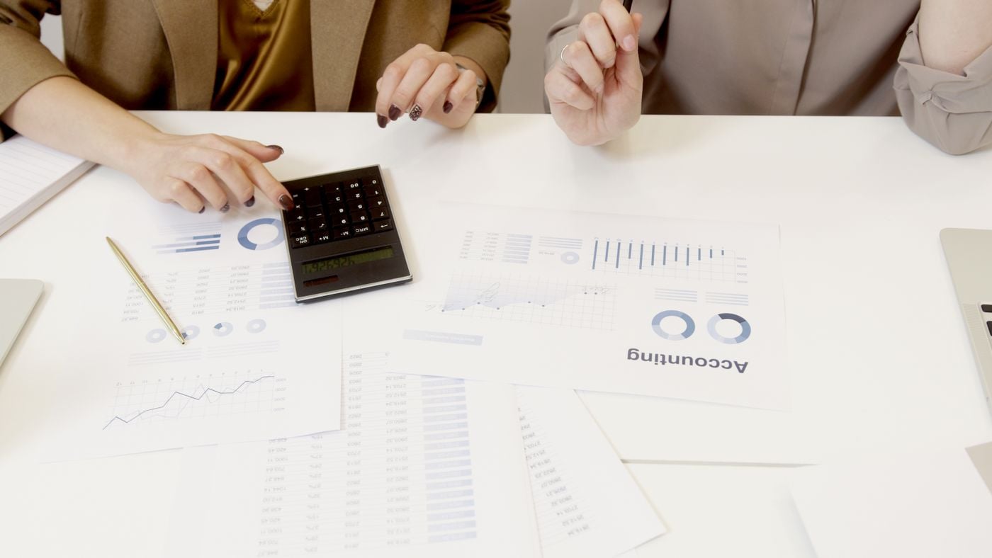 Programa de Referidos de Préstamos para Contadores y CPAs 2 Contadores revisando estados financieros con una calculadora
