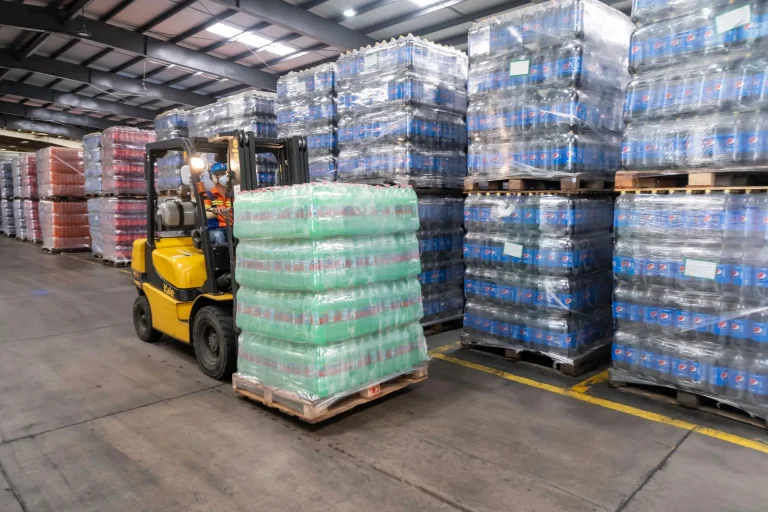 Forklift moving stacked pallets in a distribution warehouse
