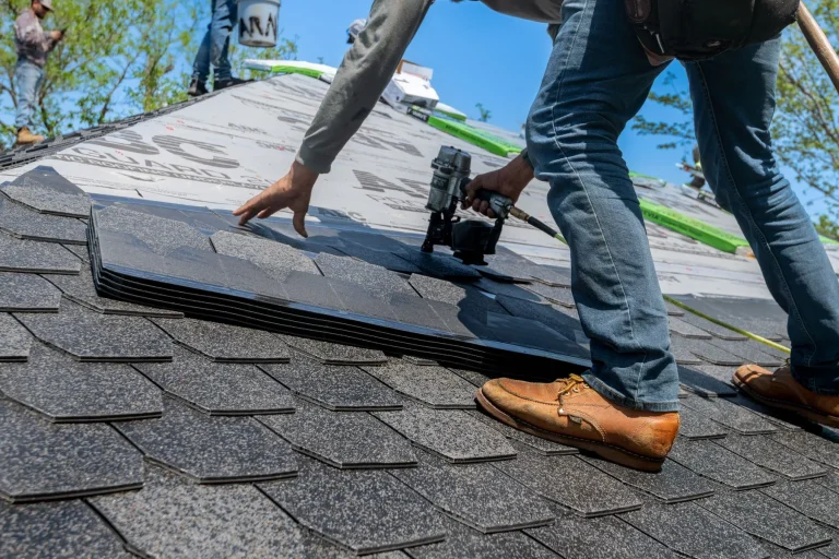 Roofing Funding 7 Roofer installing shingles on a residential roof with a nail gun