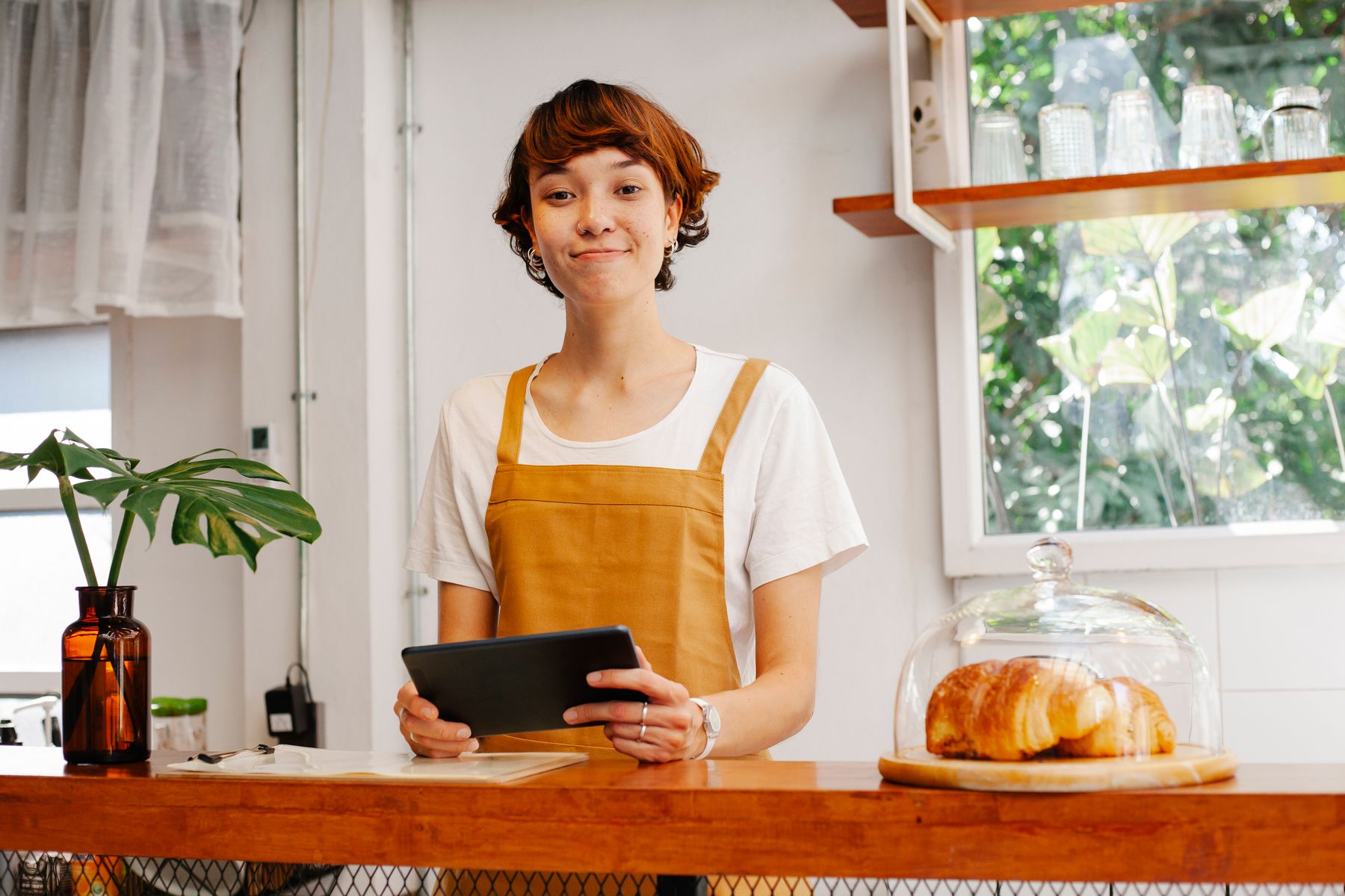 Revenue-Based Financing: How Quickly Can I Get Funded? 2 Cafe owner checking daily sales on a tablet at the counter